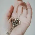 An antique skeleton key rests delicately on a person's open palm, showcasing elegant design.