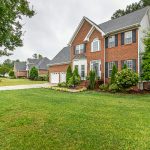 Charming two-story brick house with manicured lawn and trees, perfect family home.