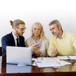 Three individuals collaborating on financial documents during a business meeting.