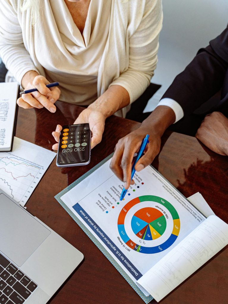Two business professionals discussing financial documents and strategies at an office desk.