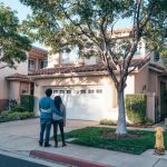 Couple hugging outside their newly purchased suburban home, showcasing togetherness and new beginnings.